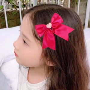 Gros plan d'un nœud en satin rose avec petit cœur porté par une petite fille