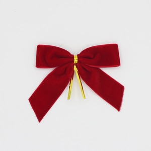 Détail de petits nœuds de Noël en velours rouge avec attaches métalliques dorées