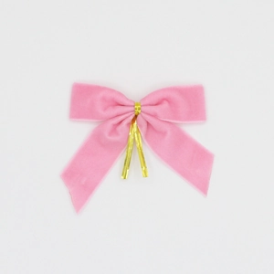 Détail de nœuds de Noël en velours rose avec attaches dorées pour décoration festive