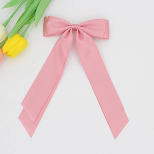 Détail d'une pince à cheveux nœud en satin rose avec de longs rubans soyeux