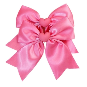 Détail de nœuds en satin rose avec embellissements de cœur mats et texture soyeuse