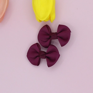 Detail shot of two wine red ribbed bow hair clips with visible fabric texture