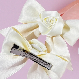 Elegante set ivoren satijnen haarstrikken met roosdetail en metalen eendenbek clip