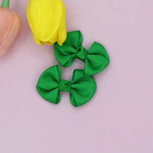 Pair of bright green grosgrain ribbon bow hair clips on a light purple background