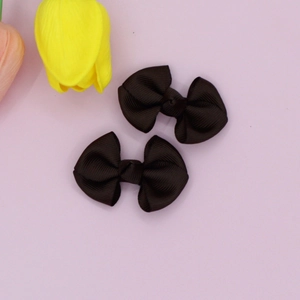 Set of two black grosgrain ribbon bow hair clips on a soft pastel background