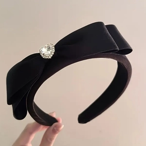 Détail d'un serre-tête en satin noir avec nœud et ornement en diamant en forme de cœur