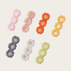 Détail de barrettes à fleurs brodées de couleurs variées aux tons pastels