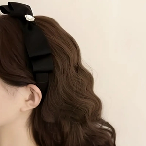 Gros plan d'un serre-tête en satin noir avec nœud et strass sur un mannequin femme