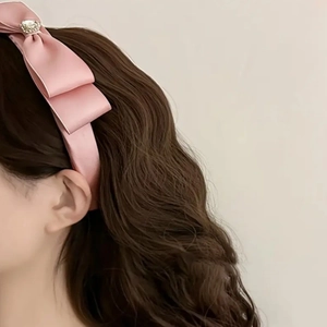 Serre-tête en satin rose avec nœud et cristal brillant sur cheveux longs ondulés