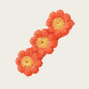 Vue détaillée d'une pince à cheveux brodée avec des tournesols orange et jaune tricotés