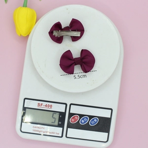 Pair of deep purple solid ribbed bow hair clips on a 5.5cm scale display