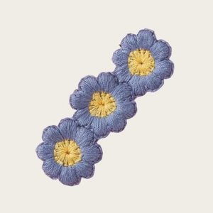 Détail rapproché d'une barrette à fleurs de tournesol brodées bleues et cœurs jaunes