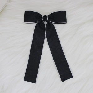 Detail of a black lace bow hair clip with white stitching on a soft white fur background