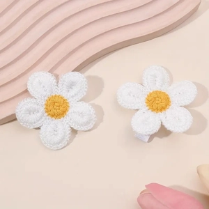 Detailed close-up of handmade crochet daisy flower hair clips in a soft warm setting
