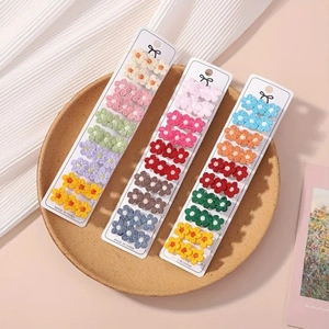 Détail de 30 barrettes à fleurs en crochet colorées sur cartes de présentation blanches