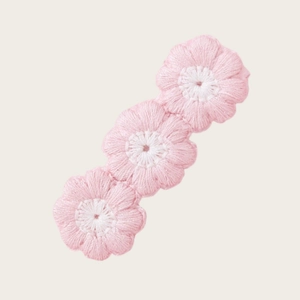 Détail de barrette à fleurs au crochet faite main avec trois fleurs roses et centre blanc