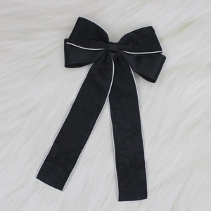 Detail of black lace bow hair clip with ribbons on soft white faux fur background