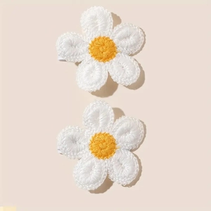 Detail of two handmade crochet flower hair clips with white petals and yellow centers