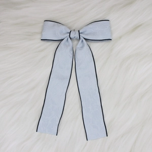 Detailed view of blue floral jacquard bow hair clip with black edges and long ribbons