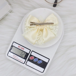 Elegant double-layered off-white lace bow hair clip weighing 12 grams on scale