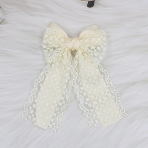Close-up of elegant beige lace hair clip with polka dot texture and satin fabric