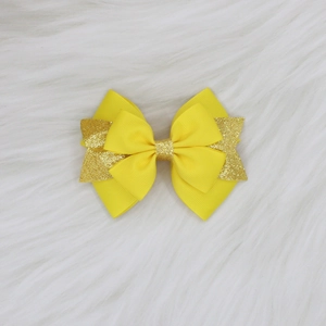 Détail du nœud papillon multicouche en ruban jaune et tissu doré pailleté pour cheveux