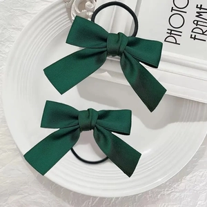 Détail de deux chouchous à nœuds en ruban vert foncé sur une assiette blanche décorative