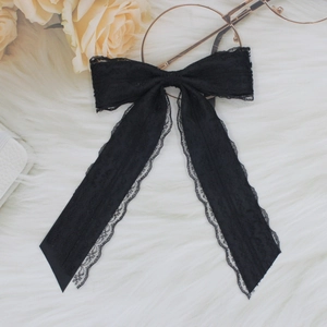 Dettaglio di un elegante fiocco per capelli in pizzo nero con lunghe code su eco-pelliccia