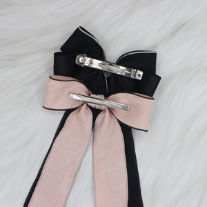 Elegant two-piece bow hair clip set with black satin and pink lace ribbons on white fur