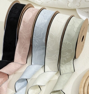 Detail of five floral embossed ribbon rolls in pastel colors for hair accessory DIY