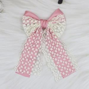 Macro detail of elegant pink satin and white floral lace layered bow hair clip accessory