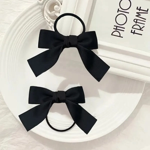 Paire d'élastiques à cheveux avec nœud en satin noir élégant sur une assiette blanche