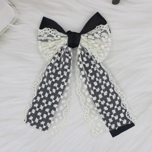Detail of elegant black and white lace bow hair clip with ribbons on white faux fur
