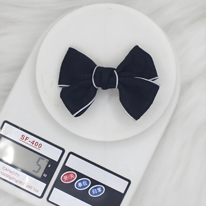 Barrette nœud jacquard noir avec bord ondulé blanc, poids de 5g sur une balance