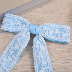 Gros plan sur une pince à cheveux en satin bleu clair avec dentelle florale blanche fine
