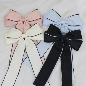 Close-up of elegant bow hair clips in pink, blue, beige, and black with jacquard texture