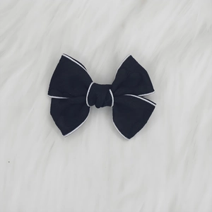Détail d'une pince à cheveux à nœud jacquard noir avec bord festonné blanc sur peluche