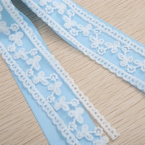 Gros plan sur un ruban de dentelle bleu clair avec broderie florale blanche pour cheveux