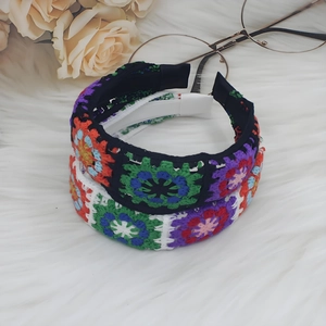 Detail of two bohemian crochet floral headbands in black and white with colorful knit flowers