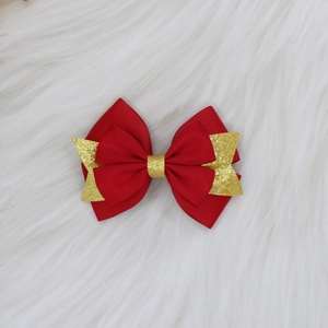 Détail d'une pince à cheveux nœud rouge et doré multicouche sur peluche blanche douce