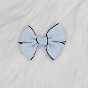 Détail de la pince à cheveux nœud jacquard bleu clair avec bordure sur fausse fourrure