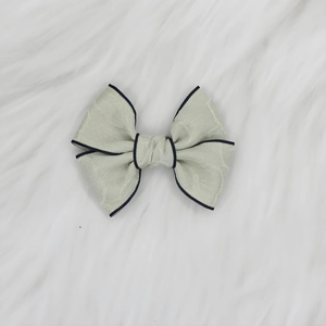Détail du nœud papillon en jacquard vert clair avec bordure sur fond de fourrure blanche
