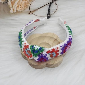 Detail of colorful knitted floral headband with elegant knot on soft white background