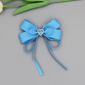 Détail de barrette nœud bleu vif avec strass en cœur et texture en ruban gros-grain