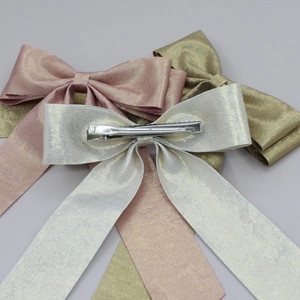 Trois barrettes nœuds aux finitions métallisées or rose, or champagne et argent