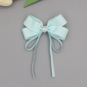 Détail d'une pince à cheveux avec nœud en ruban bleu clair et strass en forme de cœur