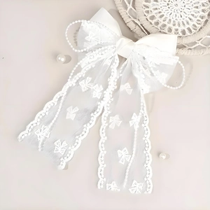 Macro shot of white lace bow hair clip with faux pearl fringe and embroidery detail