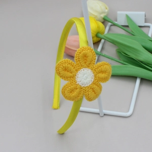 Detalle de flor de girasol tejida a ganchillo en diadema de raso color amarillo