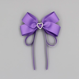 Détail d'un nœud en ruban gros-grain violet foncé avec un strass étincelant en forme de cœur