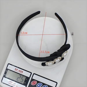 Elegant black satin headband with pearl bow accents, 12x13.5cm size shown on scale